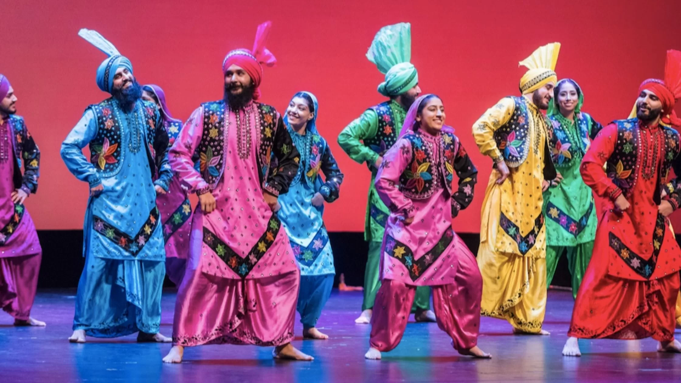 A group of dances doing bhangra on stage.