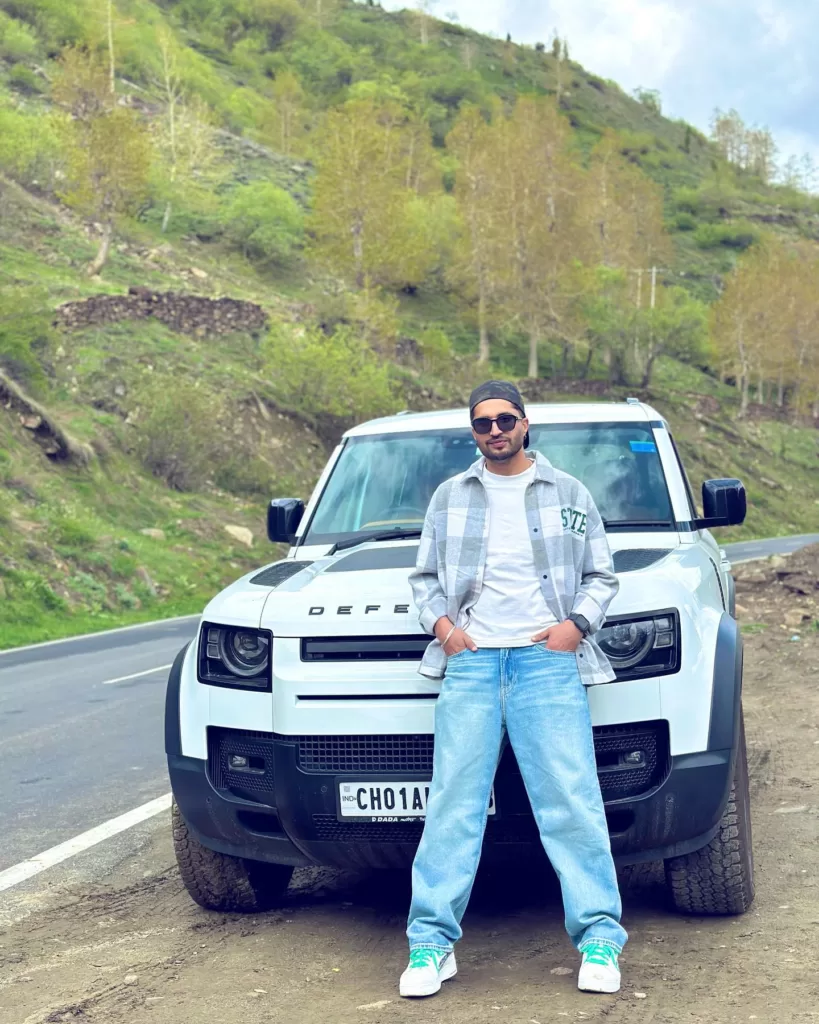 Jassie Gill posing in front of his car in hills. 