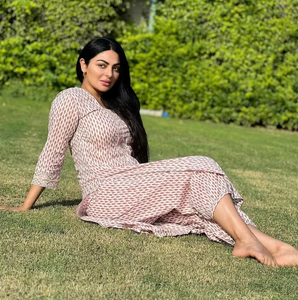 Neeru Bajwa sitting on the ground. She is wearing a printed suit.